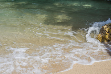 Beautiful waves of sea or ocean stormy water with white foam or froth splashing and rolling to shore on sunny day 