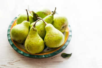 Fresh pears on a plate on white wooden table