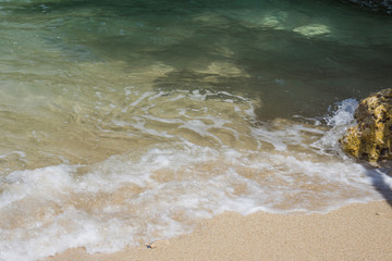 Beautiful waves of sea or ocean stormy water with white foam or froth splashing and rolling to shore on sunny day 