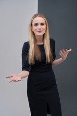 Studio portrait concept of a beautiful fashionable blond business girl standing and talking in a business dress against a multicolored background.