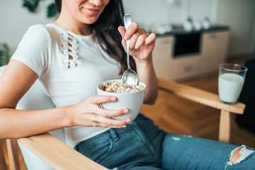 Young woman eating bowl of cereal for breakfast. Close-up.