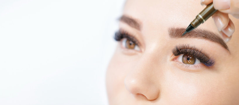 Beautiful Young Girl With Long Eyelashes Tweezing Her Eyebrows In A Beauty Salon. Woman Doing Eyebrow Permanent Makeup Correction . Microblading Brow.