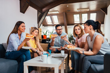 Friend talking and eating pizza at home.
