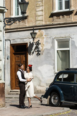 Man holds woman dressed in 30s style tender standing on the old street
