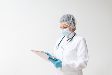 Portrait of female doctor in protective wear looking at patient's chart.