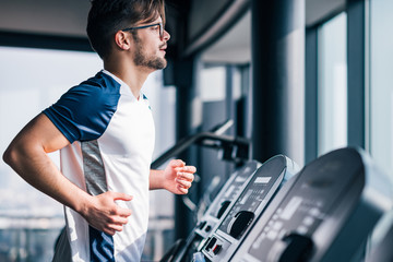 Fototapeta na wymiar Handsome man exercising in the gym, running on treadmill.