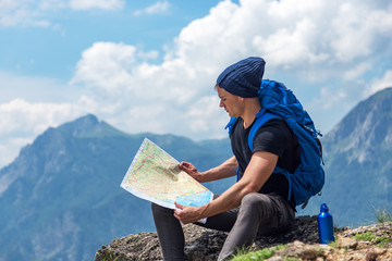 Male handsome hiker using map to navigate in nature