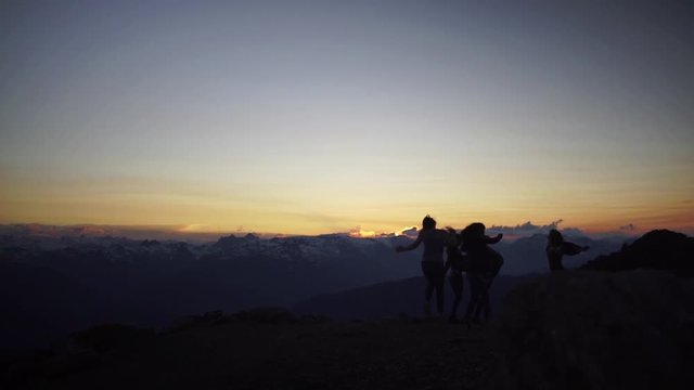 Silhouette of Girls Dancing on a Mountaintop at Sunset