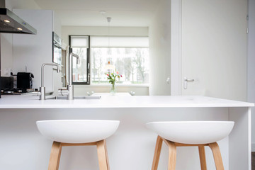 Fototapeta na wymiar Bar stools by modern white kitchen island, new and clean modern design