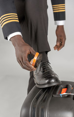 London, UK. April 2019. Airline pilot brushing his black uniform shoes.