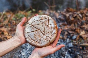 The cook holds in his hands the bread baked on the coals of the fire