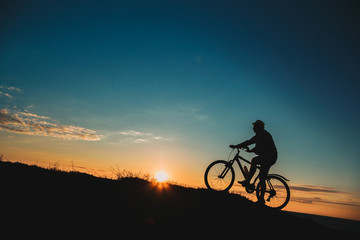 Silhouette of a male mountainbiker at sunset in the mountains