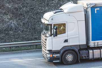 Arriving white truck on the road in a rural landscape at sunset