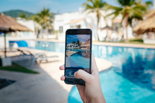 hand holding phone on background of the pool in hotel. photo camera on the screen.