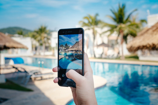 hand holding phone on background of the pool in hotel. photo camera on the screen.