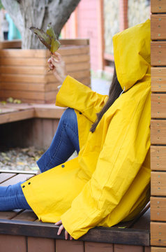 girl in a yellow raincoat sitting on the street