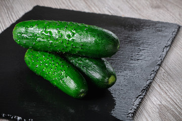 Three cucumbers on a slate.