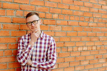 Portrait of a guy in a shirt and glasses against a brick wall
