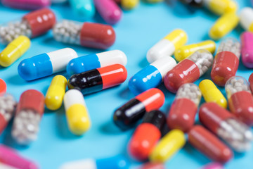 Green, yellow, red and pink pills or capsules on a blue background