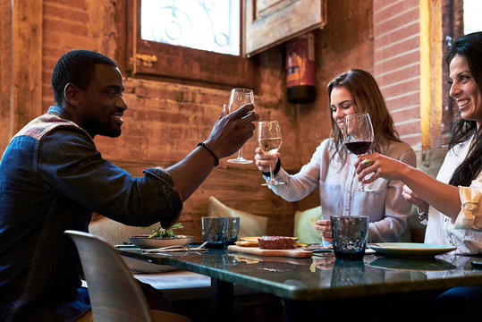 Friends toasting with glasses of wine in restaurant.