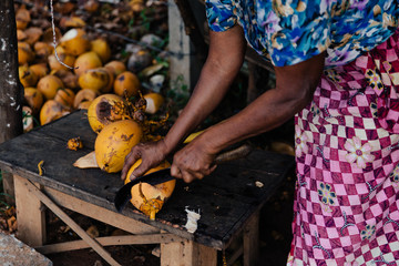 Woman Cutting Coconuts In A Market In A Tropical Location