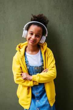 Portrait of young girl wearing headphones and denim dress