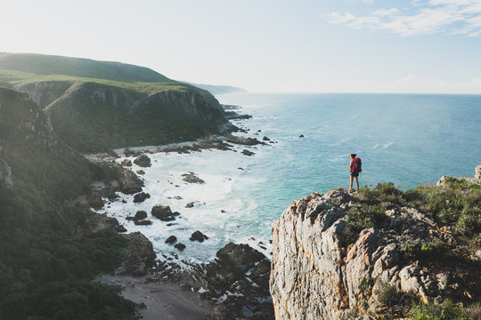 Hiker on a sea cliff overlooking a rugged scenic coastline