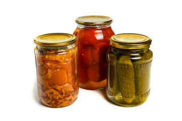 three glass jars on white background, pickled cucumbers, pickled tomatoes and canned meat