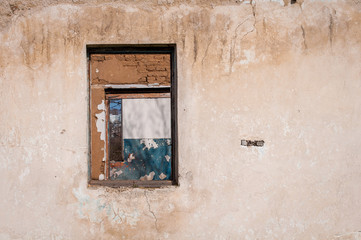 Fototapeta na wymiar The ruins of an old earthen house without a roof. Holes in the wall at the site of windows and doors