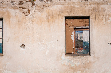 The ruins of an old earthen house without a roof. Holes in the wall at the site of windows and doors