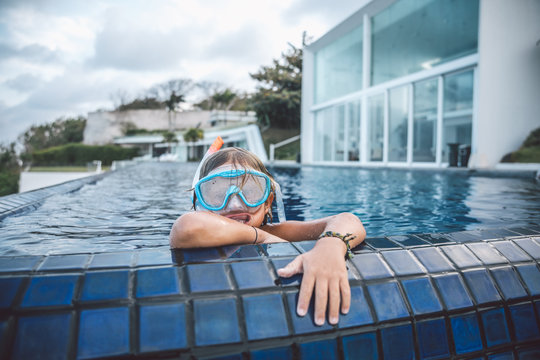 young boy with snorkeling gear looking out of a swimming pool