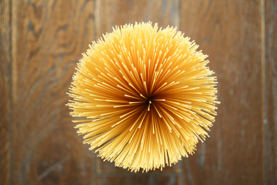 Naklejki Directly above shot of raw spaghetti on wooden background