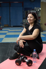 Senior woman in the gym sitting on a pink yoga mat. close-up. copy space.