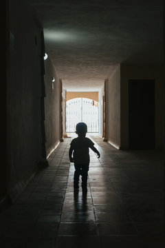 Little kid walking through a dark corridor
