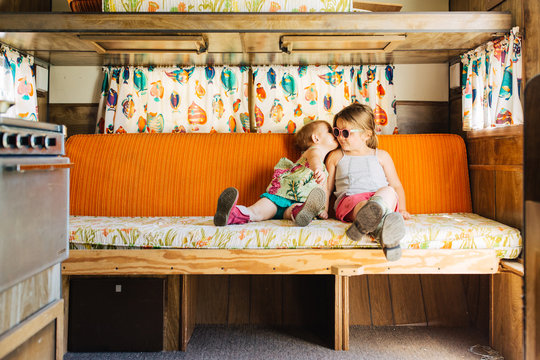 Cute toddler sisters sitting together in a vintage camper.