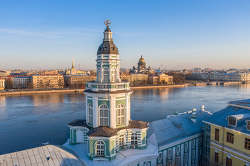 The upper part of the Kunstkamera building. View of the Neva River, the Admiralty and St. Isaac's Cathedral, in the evening, sunset at the golden hour.