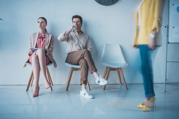 Fototapeta premium handsome employee drinking water while sitting with attractive woman