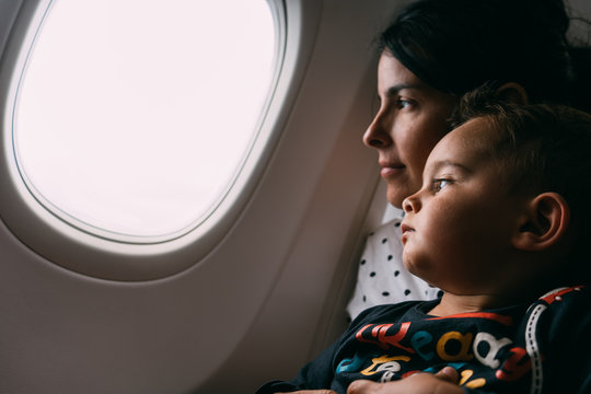 Young mother holding son and looking through aircraft window