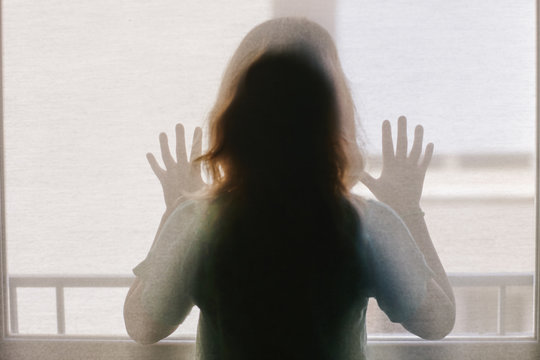 Rear view of girl looking through window