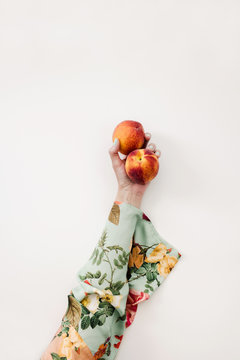 woman holding two peaches