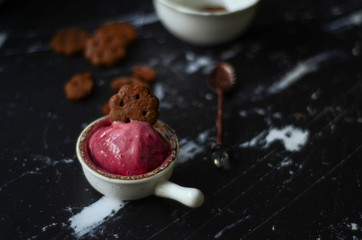 Berries ice cream in a white bowl with chocolate cookies   on dark background. Summer vibes