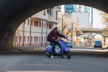 Young stylish male with colorful motor scooter