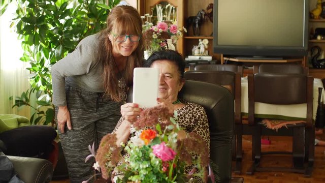 Old mom and daughter using tablet for video call
