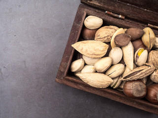 Assortment of nuts in a wooden box on a black background - healthy snack. Top view. Copy space