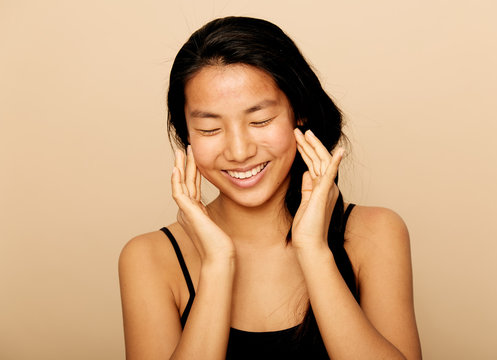 Young natural asian woman portrait applying moisturiser.