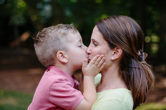 Cute young boy giving his mother an affectionate kiss on the mouth