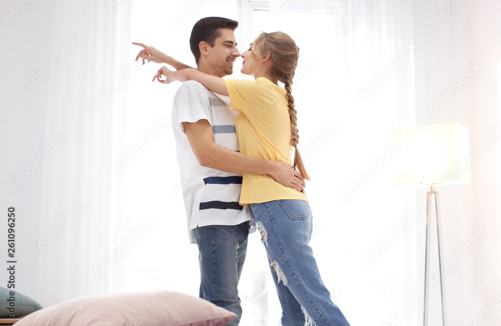 Poster cute young couple dancing indoors