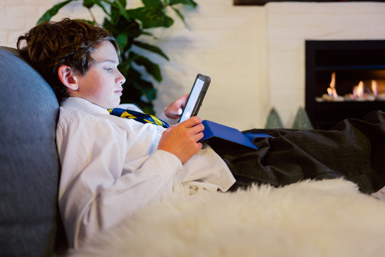 Boy transfixed and lit by the screen of a tablet