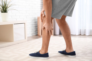 Man suffering from leg pain at home, closeup