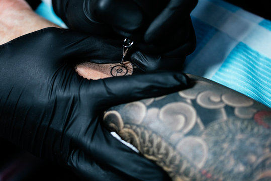 Closeup of asian tattooer makes a tattoo
